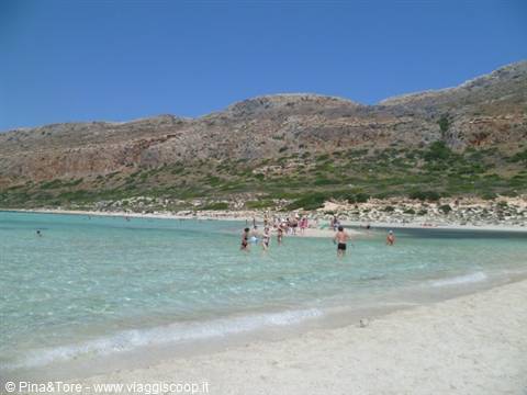 Bathers in the turquoise water of Balos lagoon, white sand and arid hills