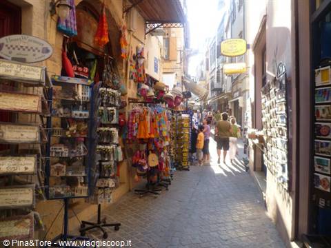 Tourists browsing souvenir stalls in a narrow Chania alley
