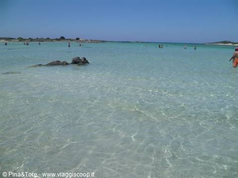 Clear turquoise water with swimmers among rocks and white sand, Crete