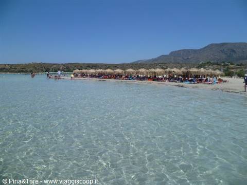 Clear turquoise water, straw umbrellas and bathers on Elafonisi beach