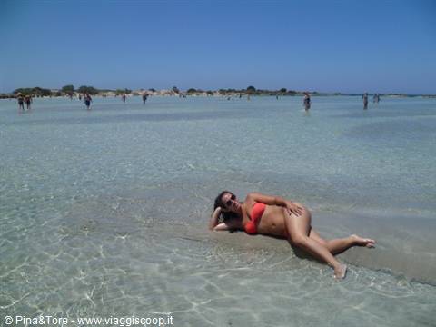 Woman in red bikini lying in the shallow turquoise lagoon of Elafonisi
