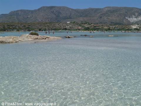 Shallow turquoise water and rocks in front of Elafonissi mountains