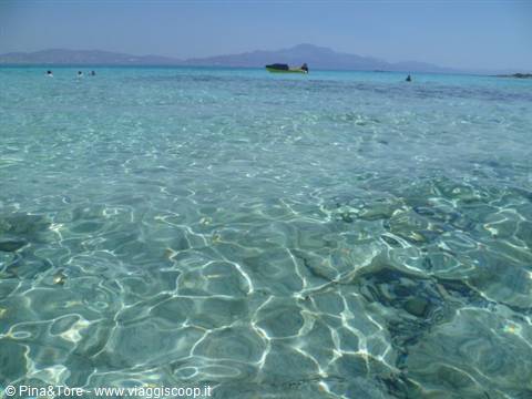 Clear turquoise water over rocky seabed, boats and swimmers at Elafonisi