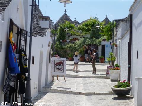 Tourists walking among white trulli houses with conical roofs in Alberobello