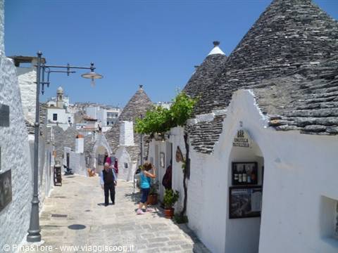 Trulli houses in Alberobello: stone cone roofs, white walls, tourists strolling the lane