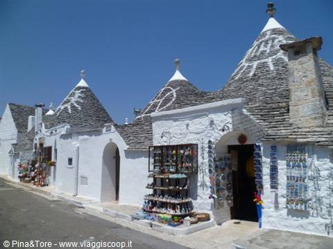 Trulli in Alberobello, whitewashed stone cones with painted symbols, souvenirs displayed