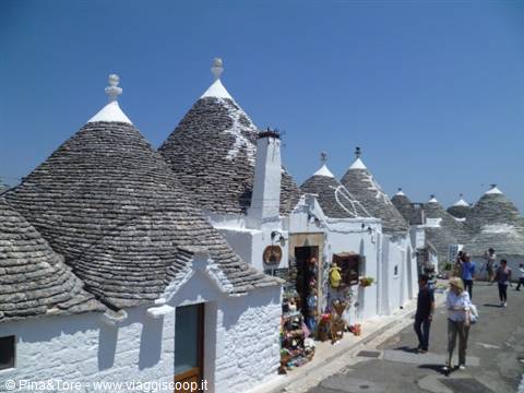 Trulli houses of Alberobello, dry-stone conical roofs, tourists walk in sunshine