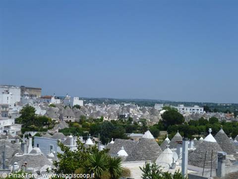 The stone conical roofs of Alberobello's trulli under a blue sky