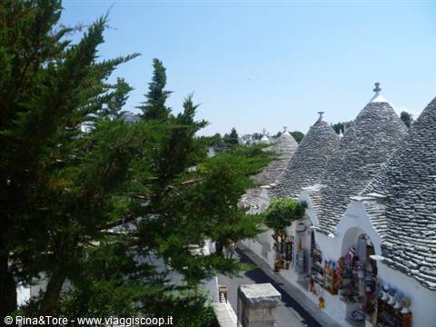 Trulli houses of Alberobello, stone cone roofs among pines and souvenir shops
