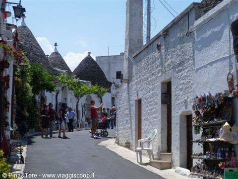 Tourists photograph the trulli of Alberobello, white stone houses with conical roofs