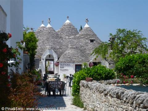 Trulli of Alberobello with conical stone roofs, restaurant in the sun