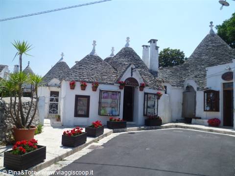 Trulli houses in Alberobello with stone conical roofs and red flowers