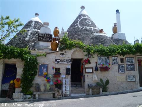 Stone conical-roof trullo in Alberobello, decorated with signs and ceramics