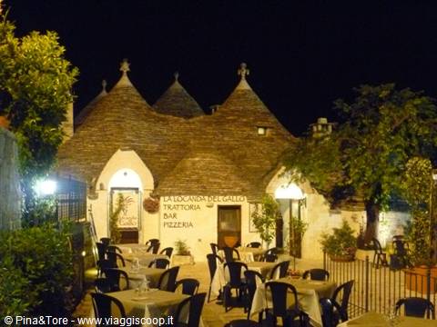 Trulli in Alberobello, outdoor restaurant with set tables at night