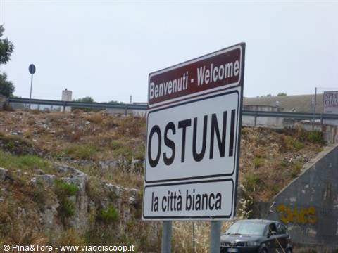White welcome road sign for Ostuni, la città bianca, under overcast sky