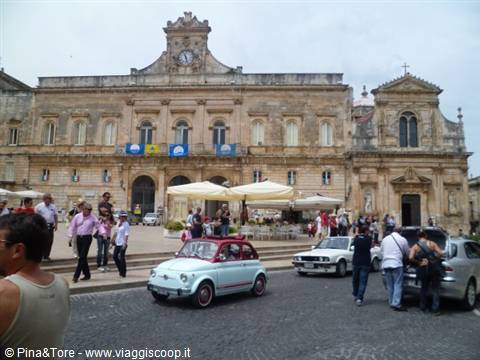 Vintage Fiat 500 in front of the baroque clocked palazzo in Ostuni