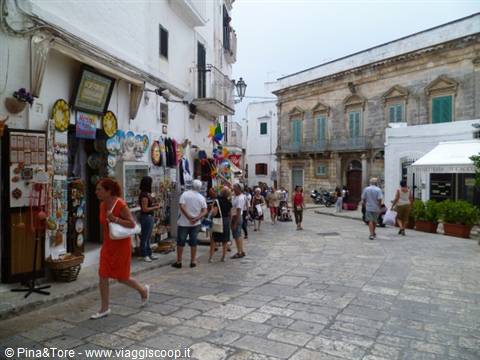Tourists browsing ceramic stalls on the whitewashed street of Locorotondo