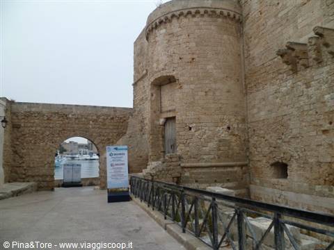Round stone tower of Otranto castle, boats visible through the arch