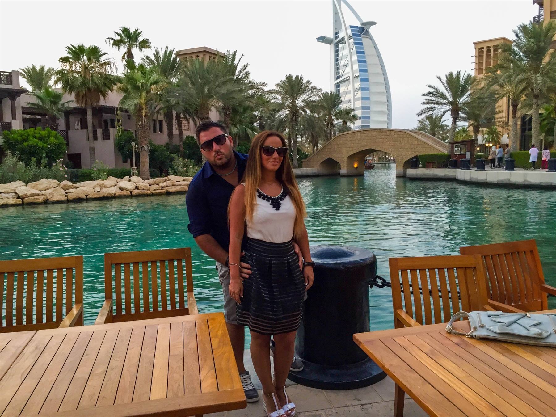 Coppia di turisti in terrazza sul canale, sullo sfondo il Burj Al Arab