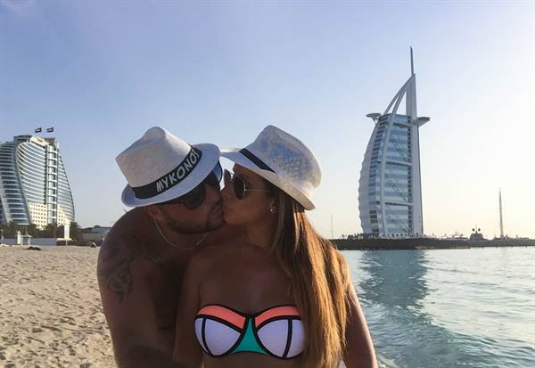 Couple in straw hats kissing on the beach in front of Burj Al Arab