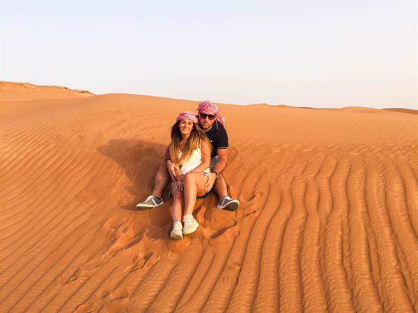 Couple in keffiyeh sitting on a red sand dune in the desert