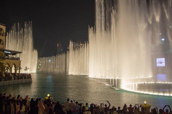 Illuminated fountains dancing on the lake at night, crowd photographing, Dubai