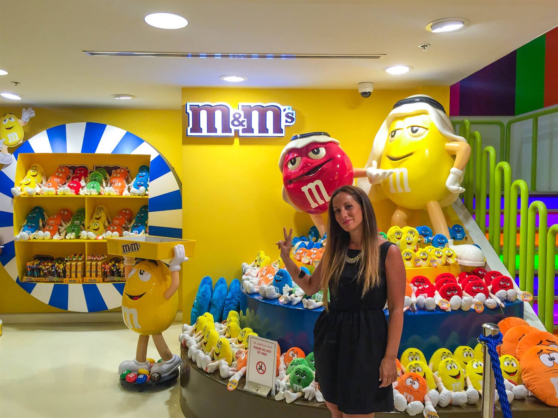 Donna accanto ai pupazzi giganti M&M in un negozio colorato