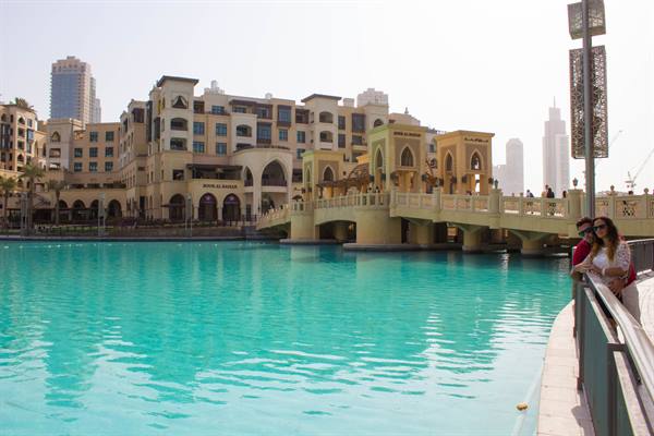 Tourists by the turquoise lake near Souk Al Bahar bridge in Dubai