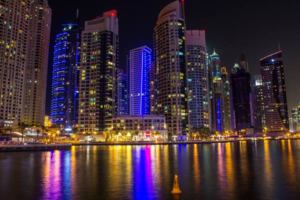 Illuminated Dubai Marina skyscrapers reflected in the water at night