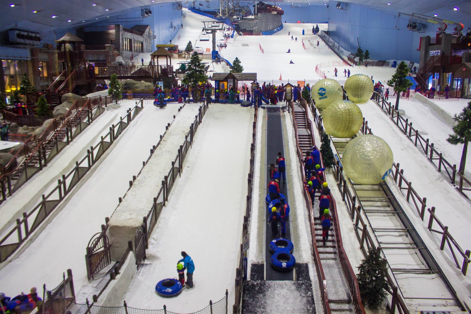 Pista coperta di neve con scivoli, zorb giganti e sciatori, Ski Dubai