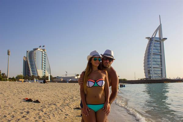 Couple in hats on Dubai beach with the Burj Al Arab behind