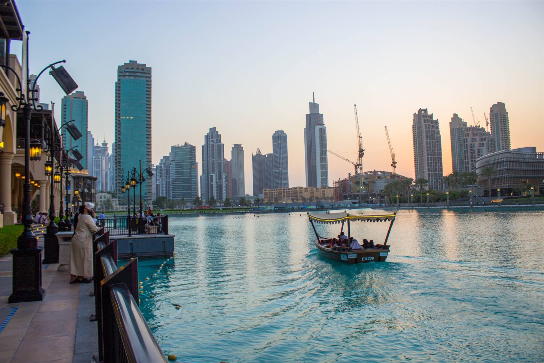 Barca tradizionale con passeggeri sulla laguna davanti ai grattacieli di Dubai