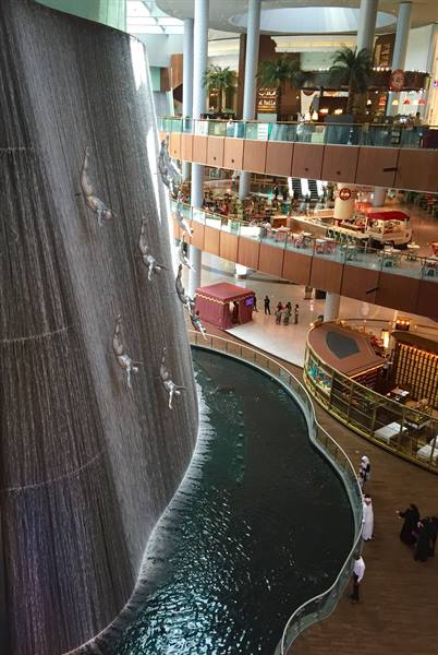 Indoor waterfall with diver sculptures at Dubai Mall, visitors on balconies