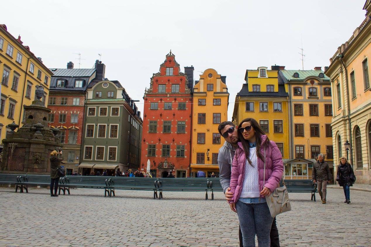 Coppia su piazza Stortorget a Stoccolma, case colorate in mattone e intonaco, cielo grigio