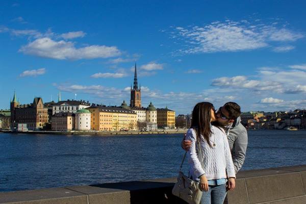Couple kissing in front of Riddarholmen, Stockholm, under a blue sky