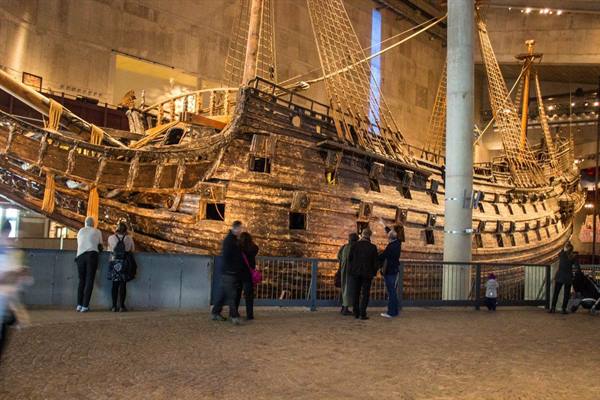 Visitors in front of the wooden Vasa warship at Stockholm museum, warm artificial light
