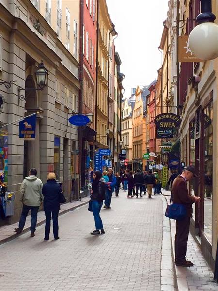 Cobblestone street in Gamla Stan, Stockholm, colorful facades and people browsing shop windows