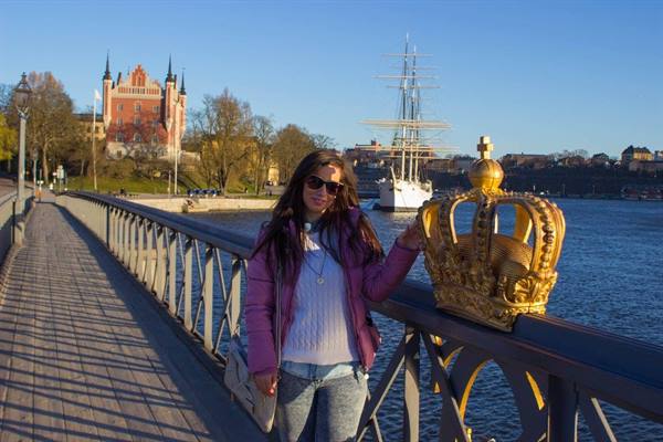 Woman on Skeppsholmsbron bridge in Stockholm, beside the golden crown on the railing