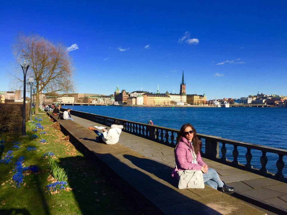 Donna seduta lungo la passeggiata di Stoccolma, Riddarholmen sull'acqua