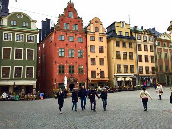 Tourists walking in Stortorget square, Gamla Stan, among colorful baroque facades
