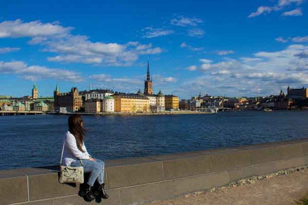 Girl sitting on granite wall facing Riddarholmen, Stockholm