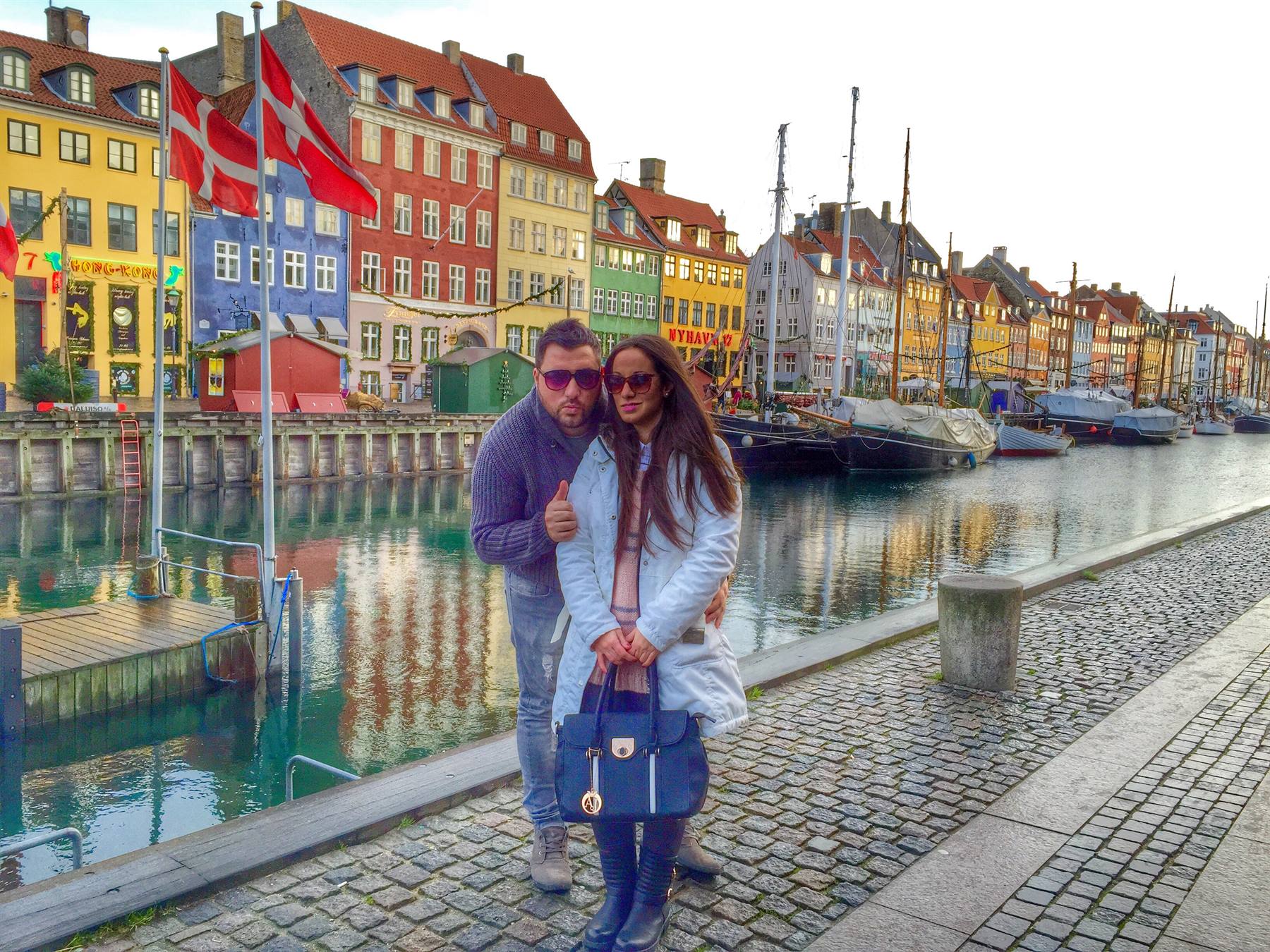 Coppia lungo il canale Nyhavn di Copenaghen tra case colorate e barche
