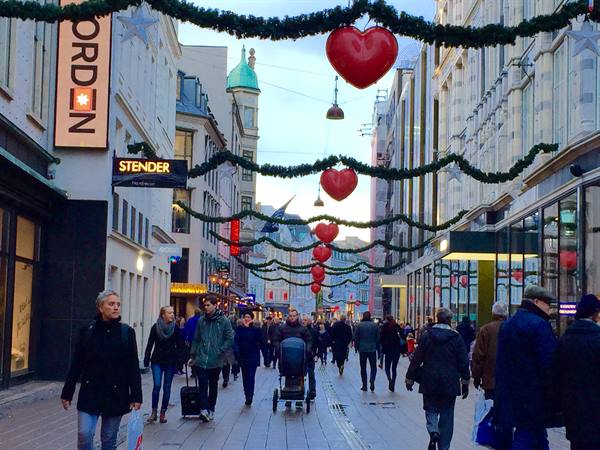 Shoppers strolling Copenhagen's pedestrian street decorated with garlands and red hearts