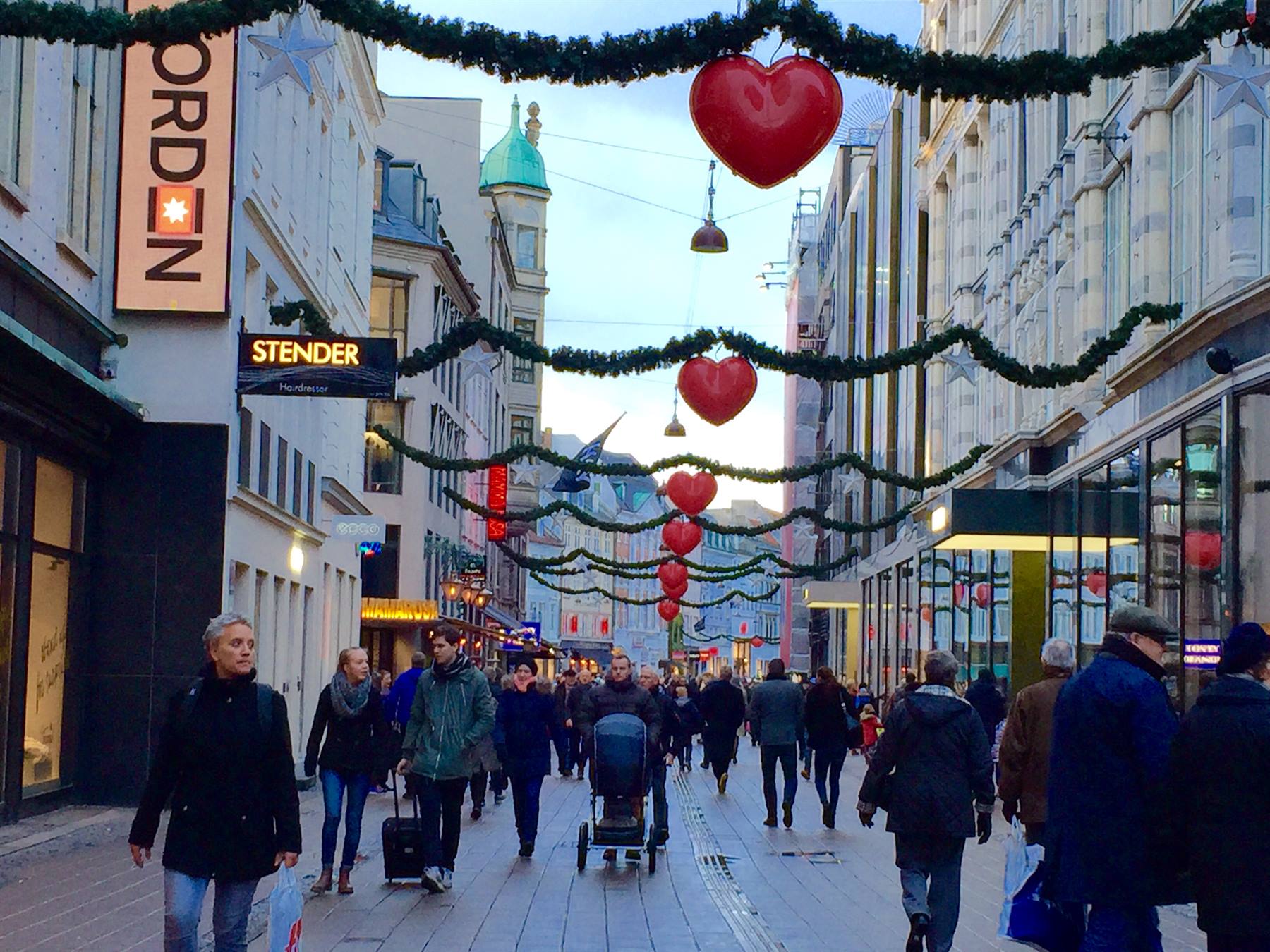 Pedoni sulla via dello shopping di Copenaghen decorata con ghirlande e cuori rossi