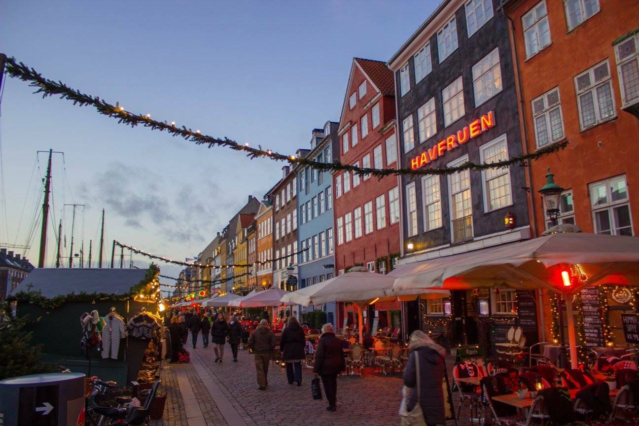 Nyhaven a Copenaghen: case colorate illuminate, mercatino natalizio e persone lungo il canale