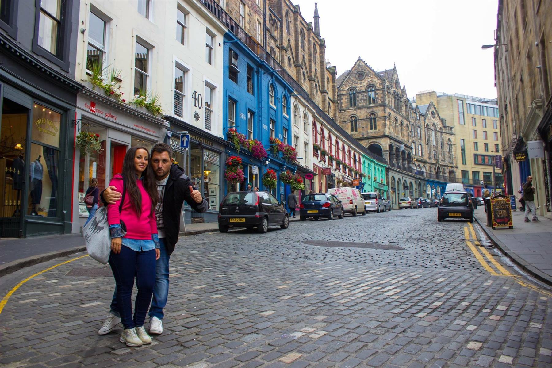 Coppia di turisti su Victoria Street, Edinburgh, tra facciate colorate e sampietrani