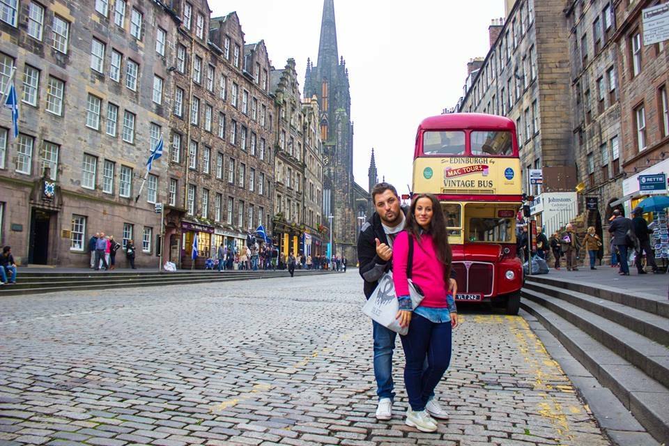 Coppia davanti a un autobus a due piani rosso sulla Royal Mile di Edimburgo