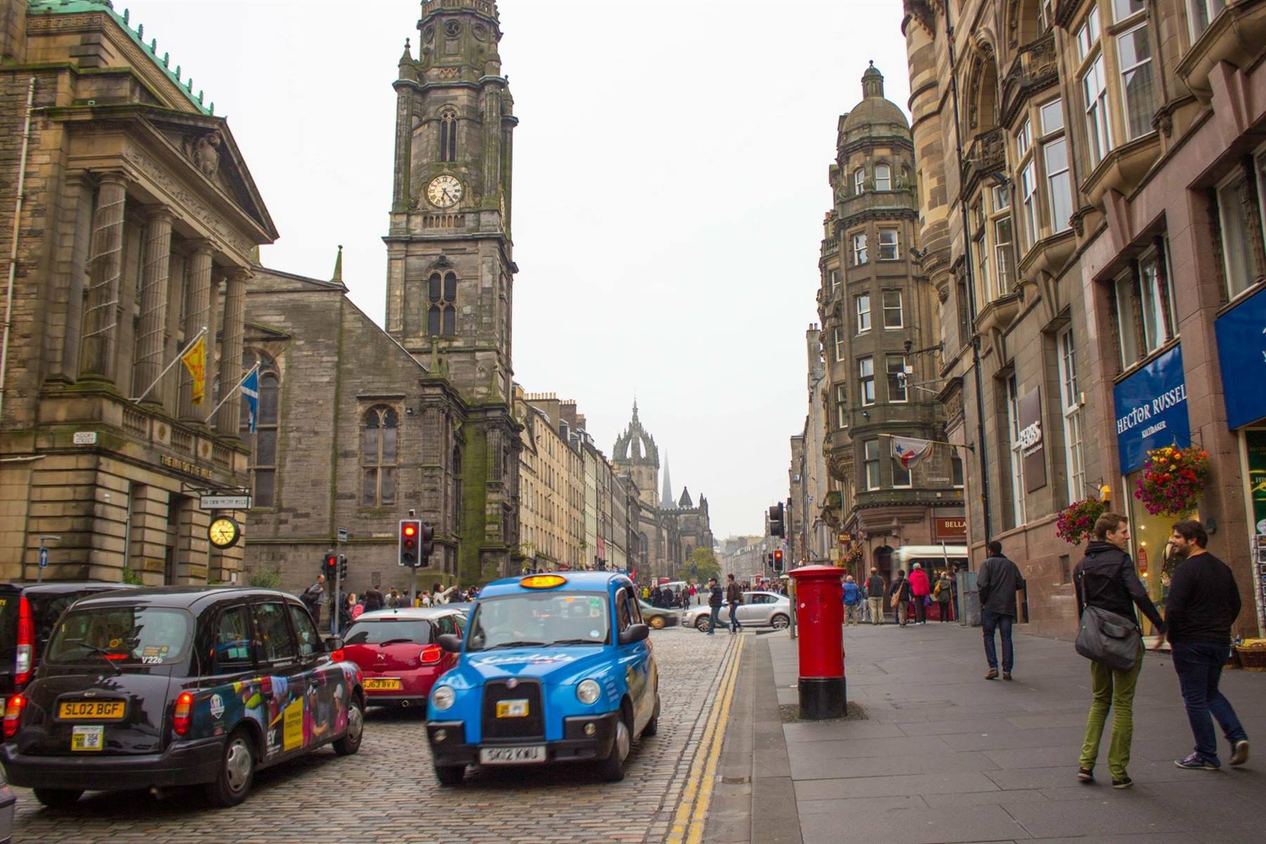 Taxi blu su Royal Mile, Edimburgo, vicino alla torre con orologio di Tron Kirk