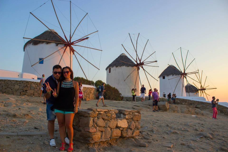 Turisti davanti ai celebri mulini a vento di Mykonos al crepuscolo