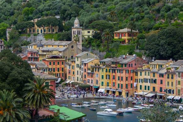 Colorful houses overlooking Portofino harbor, boats and crowds along the waterfront